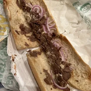 a half eaten sandwich with meat and onions