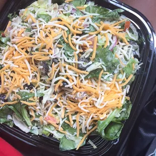a salad with cheese and lettuce in a plastic container