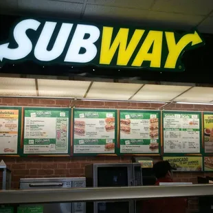 a subway menu on a brick wall