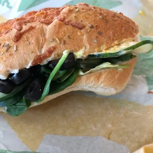 a sandwich with lettuce, black olives, and cheese