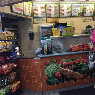 a woman standing in front of a counter in a subway