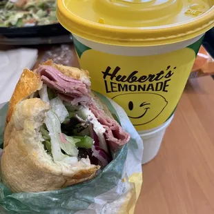 a person holding a sandwich and a drink