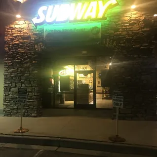 the entrance of a subway restaurant at night