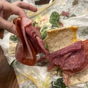a person picking up a sandwich from a wrapper