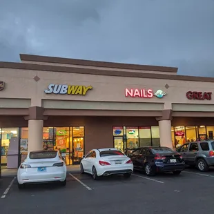 cars parked in front of a subway nail salon