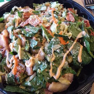 a bowl of salad with dressing and a fork
