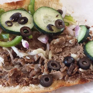 a sandwich with meat, cucumbers, and onions