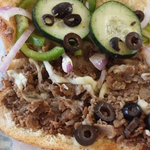 a sandwich with meat, onions, and cucumbers