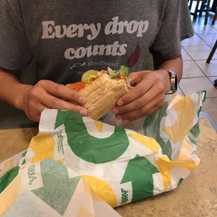 a man sitting at a table eating a sandwich