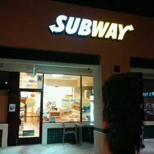 the entrance of a subway restaurant at night