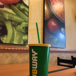 a green cup with a straw sitting on a table