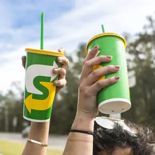 a woman holding two cups of coffee