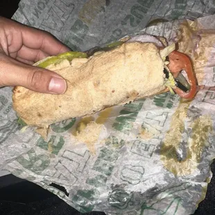a person holding a sandwich in a wrapper