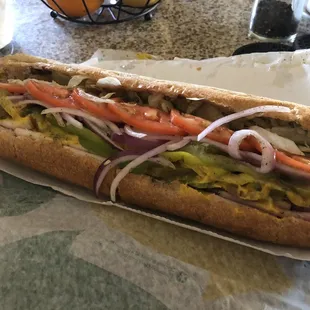 a sub sandwich with onions, tomatoes, and lettuce