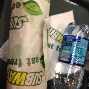 a sandwich wrapped in a paper towel and a bottle of water