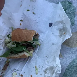 a half eaten sandwich with lettuce and meat