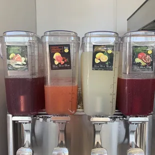 a row of juice dispensers on a counter