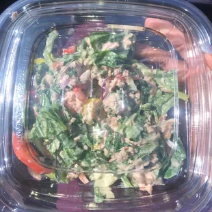 a person holding a plastic container with a salad in it