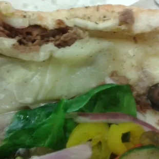 a closeup of a sandwich with meat and vegetables