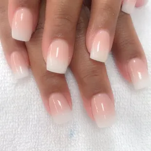a closeup of a woman's hand with a white and pink french manicure