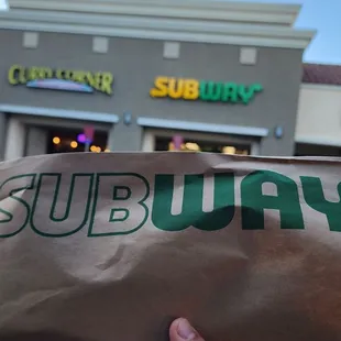 a hand holding a subway subway sandwich
