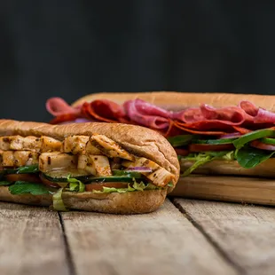 two sub sandwiches on a wooden table