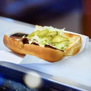 a hot dog with avocado on a bun