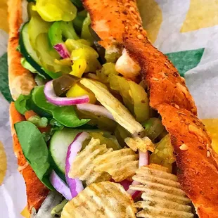 a hot dog with chips and vegetables