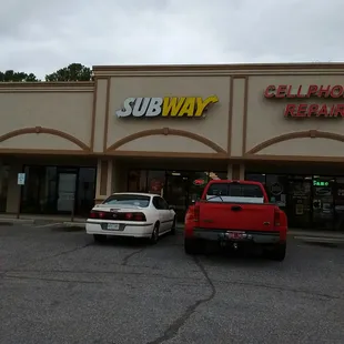 two cars parked in front of a subway restaurant