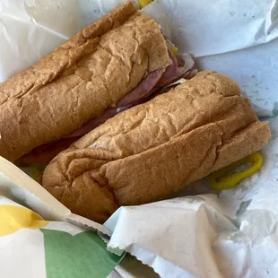 two sub sandwiches in a basket on a table