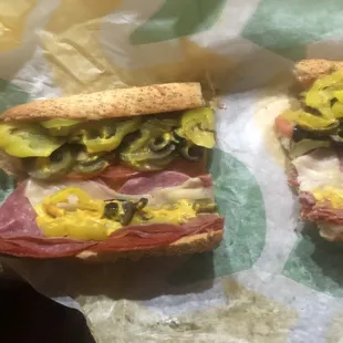 two sub sandwiches with pickles and cheese