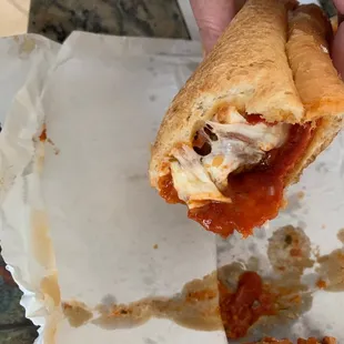 a hand holding a half eaten sandwich