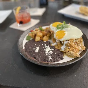 Chilaquiles - homemade tortilla strips with roasted chicken, crema and fried eggs with choice of roja or mole sauce