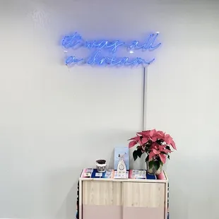 a blue neon sign above a pink cabinet
