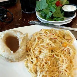 a plate of spaghetti with gravy and mashed potatoes