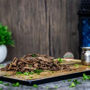 a pile of sliced beef on a cutting board