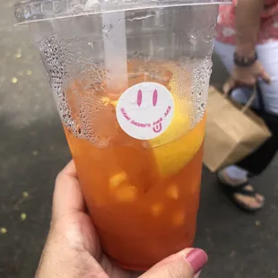 a hand holding a cup of iced tea