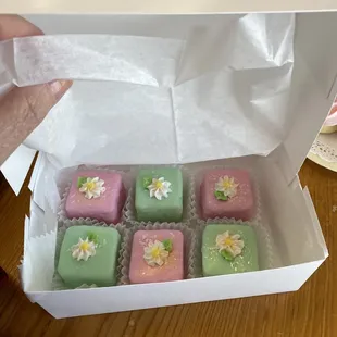 a person holding a box of small cakes