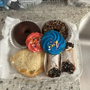 Apple turnover, sugar cookies, mini chocolate chip cannolis, chocolate glazed donut and pecan donut.