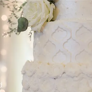 White fondant lattice on buttercream with fluffy rosettes.