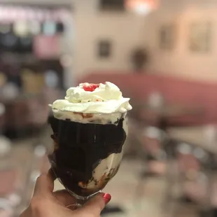 a hand holding a chocolate sundae