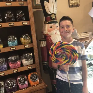 a young boy holding a lollipop