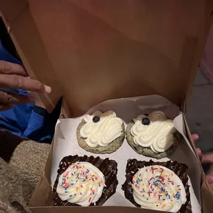 a box of cupcakes with frosting and sprinkles