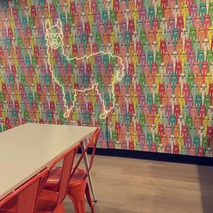 a table and chairs in front of a colorful wall