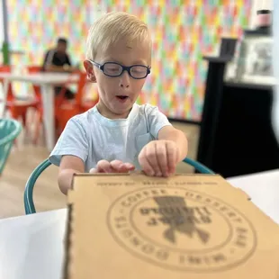 a young boy opening a pizza box