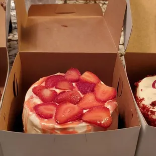 three cakes in boxes with strawberries