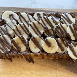 a chocolate drizzle drizzle on top of a waffle topped with bananas