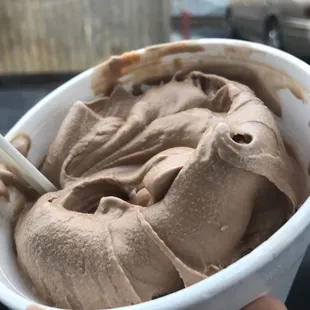 a hand holding a bowl of ice cream
