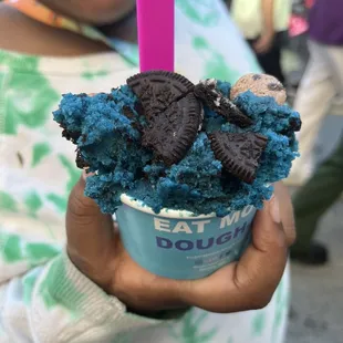 a child holding a cup of ice cream with oreo cookies