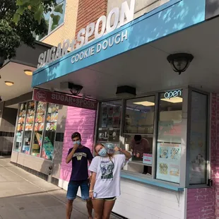 two people standing outside of a store